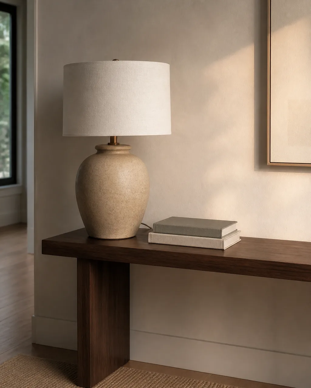 A large rounded ceramic table lamp with a cream linen shade dominating one end of a console table with breathing room on the opposite side